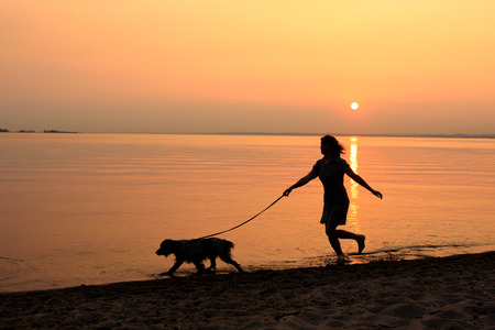 Walking the dog along the beachの写真素材
