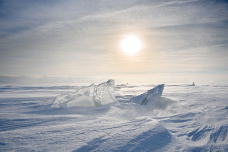 Boundless icy landscape during a snowstorm at sunset in winter.の写真素材
