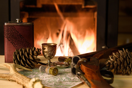 Knife Compass and map lie by the fire. In a fireplace fire burns.