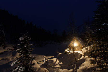 The lantern burns near the house on the river bank in winter.の写真素材
