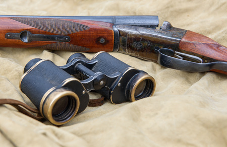 Vintage hunting rifle and binoculars lie on a khaki tent.