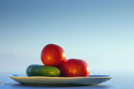 Fresh red tomatoes and cucumber on summer sunset background. Mediterranean summer or autumn concept. Space for text.の写真素材
