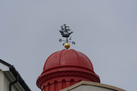 a metal weathervane in the shape of a galleon on a pagoda rooftop