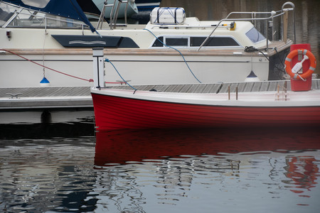 A cruiser and a row boat moored in a marinaの写真素材