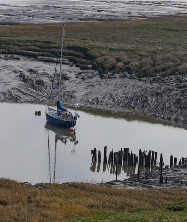 A yacht anchored on mudflats in a basinの写真素材