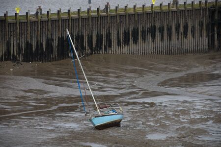 a yacht beached by the tide on mudflatsの写真素材