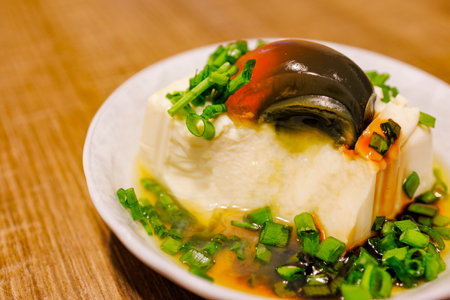 a plate of exquisite century egg tofu, sprinkled with fresh green onionsの写真素材