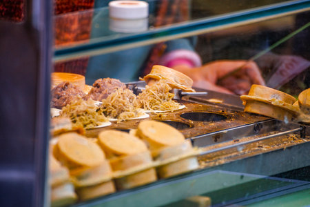 a vendor in the process of making hot and steaming wheel cakes