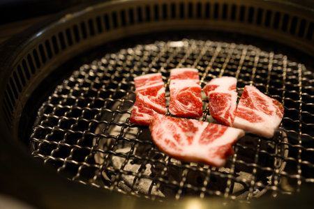 slices of beef being grilled over a charcoal fireの写真素材
