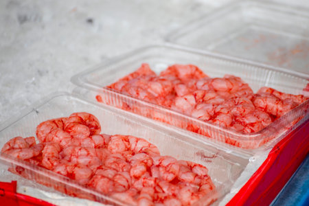 a transparent box is filled with vibrant red shrimpの写真素材
