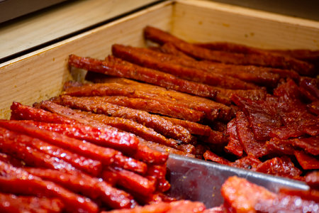 slices of red and glossy pork jerky are stacked neatly togetherの写真素材