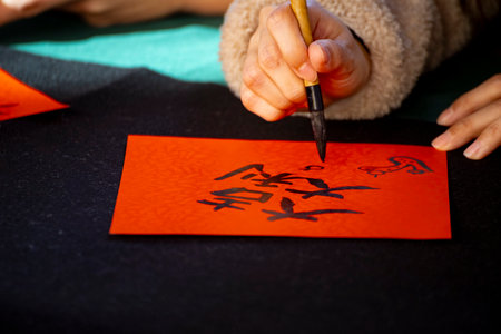 a calligrapher is concentrating on writing a Spring Festival couplet on red paper with a brushの写真素材