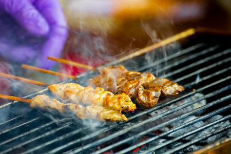 several meat skewers sizzle on the charcoal grillの写真素材