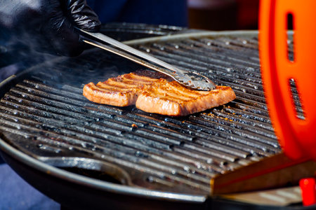 a thick pork neck steak sizzles on the charcoal grillの写真素材