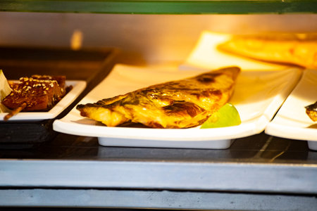 a golden-grilled fish is displayed on a stallの写真素材