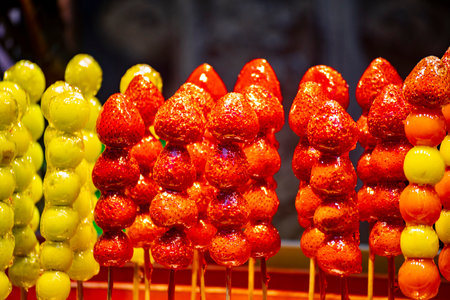 several colorful tanghulu are neatly arranged on a wooden stallの写真素材