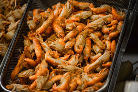 a large pile of deep-fried river shrimps in containers and on metal traysの写真素材
