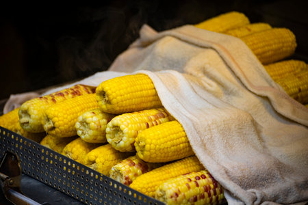 a large pile of golden corn cobs neatly stacked in a metal container