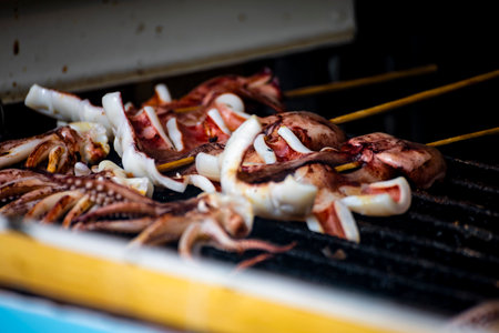 the process of squid being grilled or cooked on a hot plate. Large squid are placed on a heat source