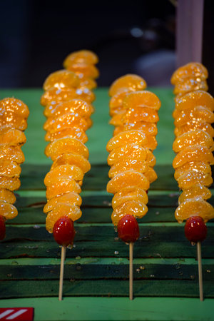 several colorful tanghulu are neatly arranged on a wooden stallの写真素材