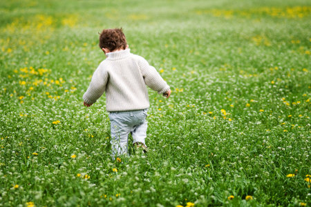Spring is coming. Boy running through grass.の写真素材