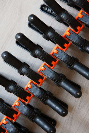 Pattern from black and orange construction clamps. A set of medium plastic clips. Clamping tools for carpentry work. Hand tools for needlework. Clamping equipment.の写真素材