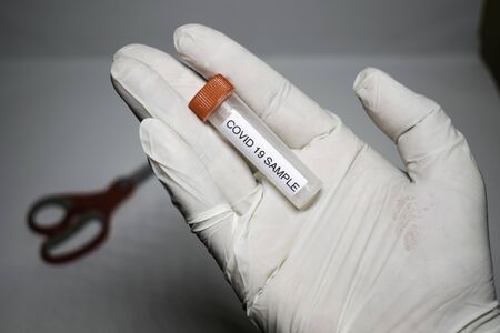 microbiologist with a tube of biological sample contaminated by Coronavirus with label Covid-19 / doctor in the laboratory with a biological tube for analysis and sampling of Covid-19 infectious diseasの写真素材