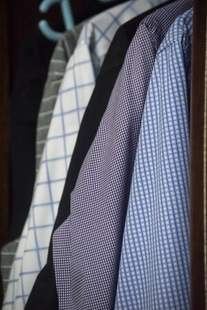 mix of men's shirts hanged in wardrobe