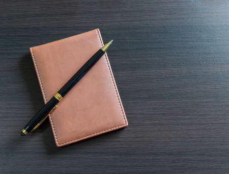 a pen and small daily note on a black tableの写真素材