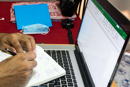 working from home, a man writing on a note book while working from homeの写真素材