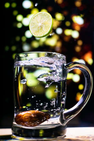 levitating lemon in to the water with light bokeh backgroundの写真素材