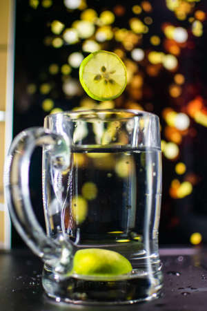 levitating lemon in to the water with light bokeh backgroundの写真素材