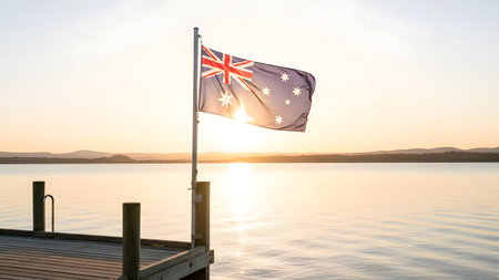 Australian flag waving on a jetty at sunset with mountains in the backgroundの素材