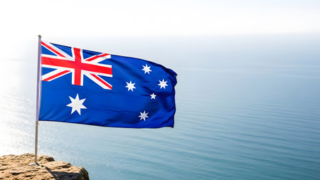 Australia flag waving in the wind over blue sea and sky background.の素材