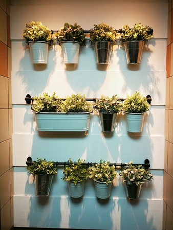 Artificial colorful flowers ports hang onto the white wall