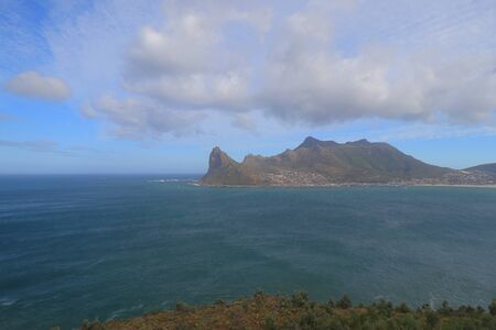 The view of Hout Bay and Atlantic Ocean with mountain peaks and range of The Sentinel, Kaptein's Peak and Oranjekloof, s seen from the viewing point along the Chapman's Peak Drive in Cape Peninsula.の写真素材