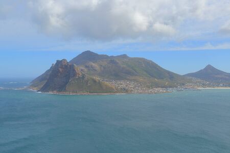 The view of Hout Bay and Atlantic Ocean with mountain peaks and range of The Sentinel, Kaptein's Peak and Oranjekloof, s seen from the viewing point along the Chapman's Peak Drive in Cape Peninsula.の写真素材