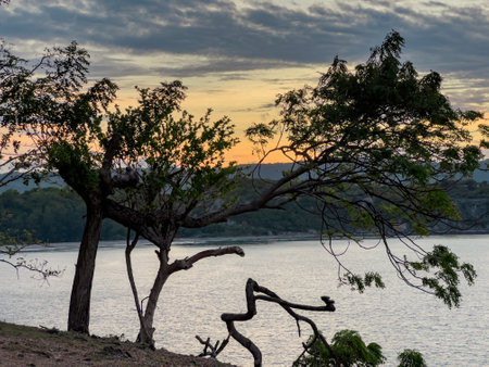 The sunset by the beach with the calm sea, showcasing the beautiful hills, creates a stunning and...