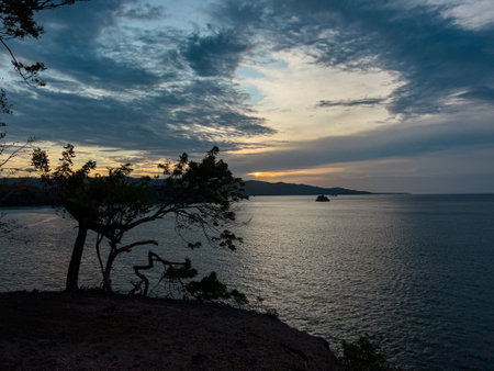 The sunset by the beach with the calm sea creates a stunning and tranquil atmosphereの写真素材