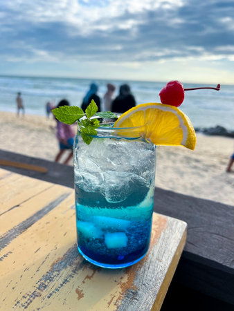 A cold and refreshing Blue Ocean Cocktail is placed on the table at a restaurant located by the beach, perfect for enjoying and very refreshing.の写真素材