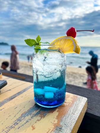 A cold and refreshing Blue Ocean Cocktail is placed on the table at a restaurant located by the beach, perfect for enjoying and very refreshing.の写真素材