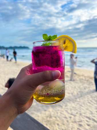 A cold and refreshing dragon fruit cocktail is held in hand at a restaurant located by the beach, perfect for enjoying and very refreshing.の写真素材
