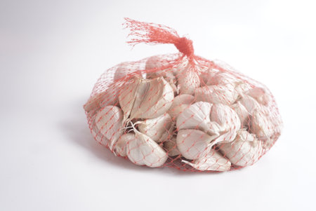 Organic Garlic in a string bag on a white background, close-upの写真素材