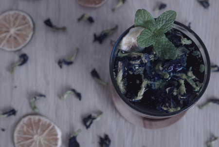 Teh Bunga Telang, Butterfly pea tea with dry lemon in a glass with wooden coaster, Flat lay, Close Upの写真素材