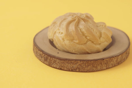 Kue Soes or choux Ã  la crÃ¨me isolated on a yellow background. Perfectly puffed and filled with a creamy filling, this classic French dessert is sure to delight. Selective Focus , Closeupの写真素材