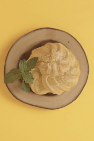 Kue Soes or choux Ã  la crÃ¨me isolated on a yellow background. Perfectly puffed and filled with a creamy filling, this classic French dessert is sure to delight. Selective Focus , Closeupの写真素材