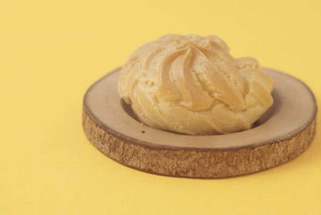 Kue Soes or choux Ã  la crÃ¨me isolated on a yellow background. Perfectly puffed and filled with a creamy filling, this classic French dessert is sure to delight. Selective Focus , Closeupの写真素材