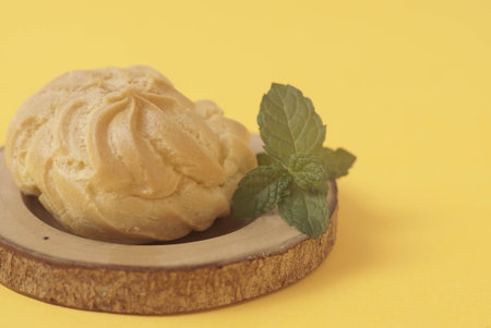 Kue Soes or choux Ã  la crÃ¨me isolated on a yellow background. Perfectly puffed and filled with a creamy filling, this classic French dessert is sure to delight. Selective Focus , Closeupの写真素材