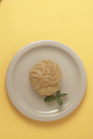 Kue Soes or choux Ã  la crÃ¨me isolated on a yellow background. Perfectly puffed and filled with...