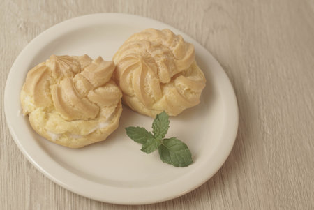 Kue Soes or choux Ã  la crÃ¨me on white plate. Perfectly puffed and filled with a creamy filling, this classic French dessert is sure to delight. Selective Focus , Closeupの写真素材